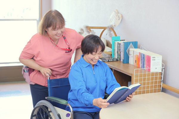 介護士と読書をする利用者さま