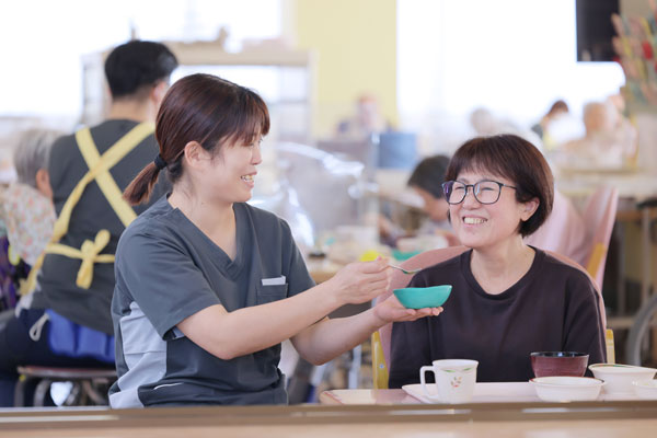 介護士と食事をする利用者さま